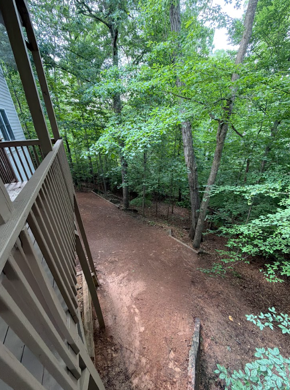 Cleared path along a deck after light land clearing, with brush removed down to soil