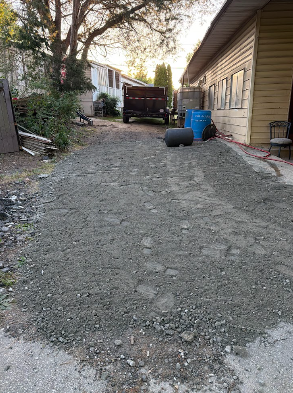 New crushed gravel driveway installed and compacted alongside a home